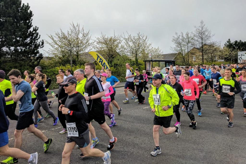 Group of people in various colours of clothing running on a road